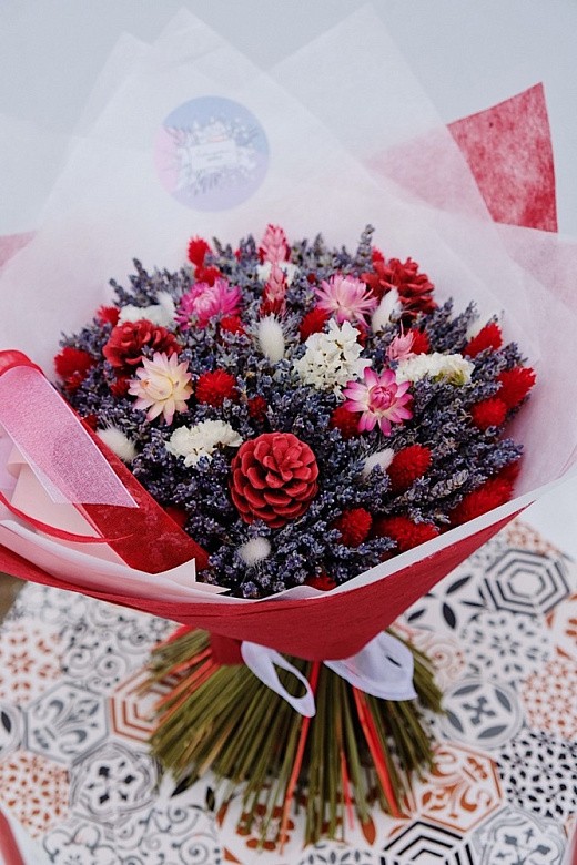 Фото яркого новогоднего букета из сухоцветов с лаваедином и шишками. 